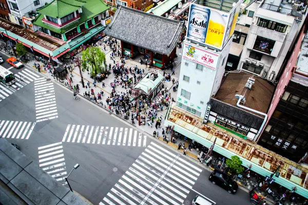 Pedestrians crossing striped roads beneath traditional rooftops