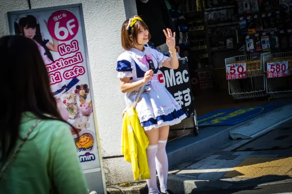 A costumed cafe worker waving on a sunlit street