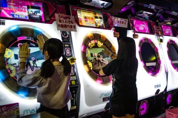 People playing illuminated rhythm games in an arcade