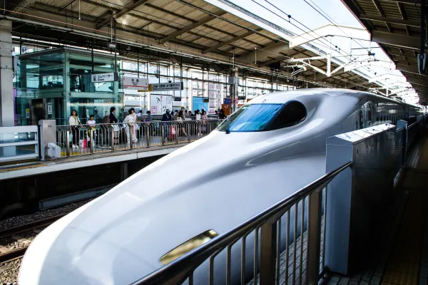 The streamlined nose of a bullet train beside a station platform