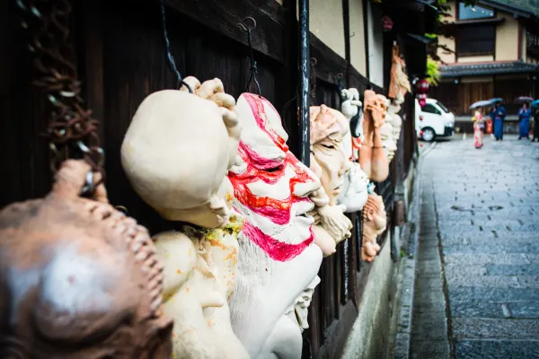 Small ceramic figures lining a wall beside a wet stone lane