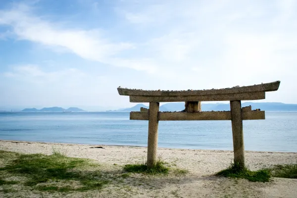 A stone torii gate facing a calm blue sea