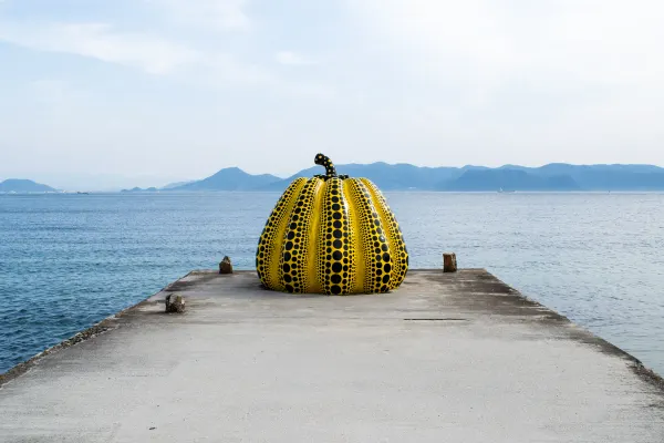 A yellow polka-dot pumpkin sculpture at the end of a pier