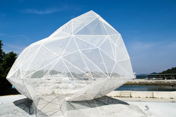 A white geometric mesh sculpture against a clear blue sky