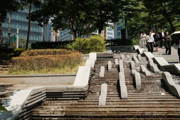 Sunlit stone steps and a stepped water feature beneath leafy trees