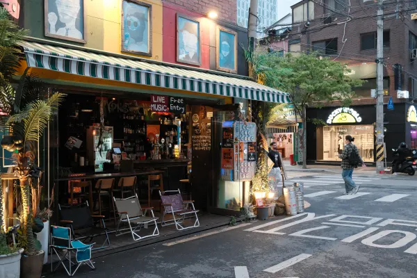 A small corner bar opening onto a narrow street at dusk