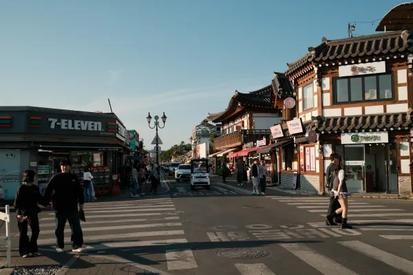 Pedestrians crossing a street lined with traditional tiled roofs