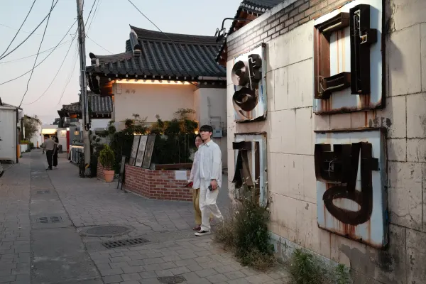 A person standing beside a worn storefront and traditional tiled roof