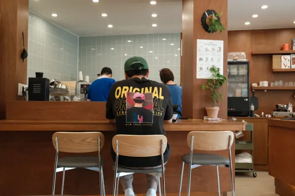 A person seated between empty chairs at a warm wooden cafe counter