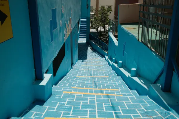 A steep blue staircase descending between vivid turquoise walls