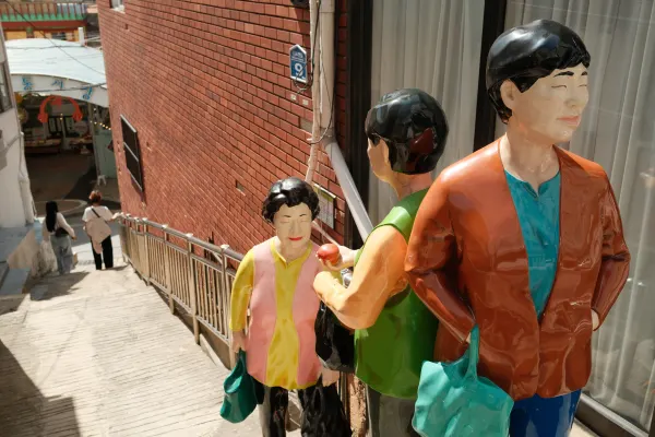 Colourful human sculptures beside a steep staircase and brick wall