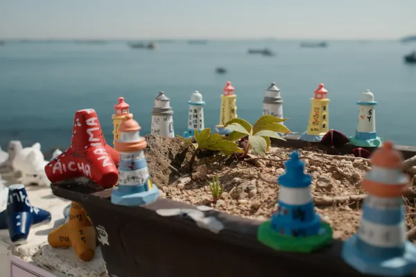 Miniature coloured lighthouses arranged in a planter overlooking the sea