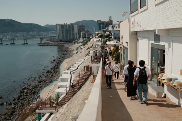 People walking along a narrow hillside promenade above the coast