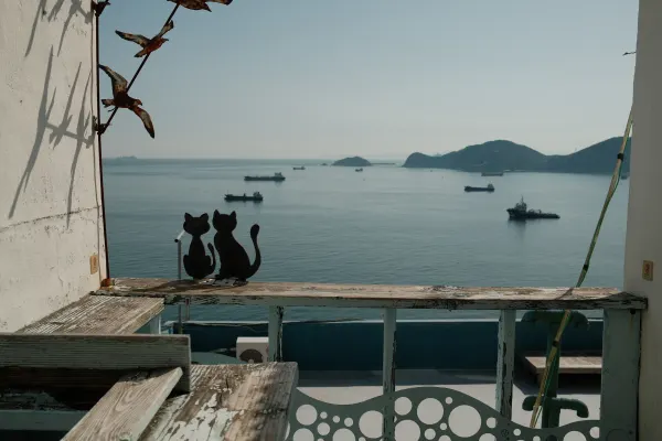 Two decorative cat silhouettes overlooking boats on a calm blue sea