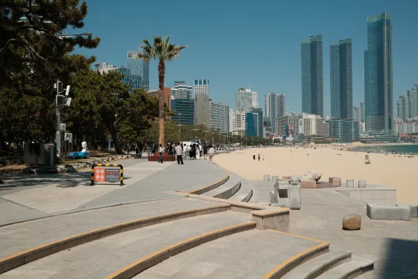 Curving stone steps leading towards a sandy beach and tall waterfront towers
