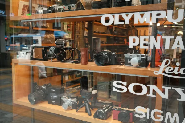Vintage cameras behind a shop window lettered with camera brand names