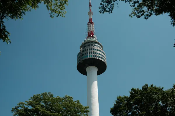 A red and white observation tower framed by green tree branches