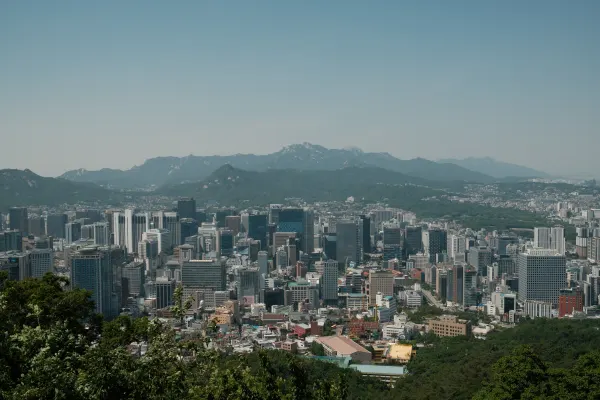 A dense city skyline stretching towards a distant mountain ridge