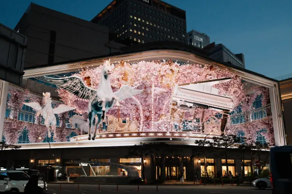 An illuminated display of white horses and pink blossoms above a city shop