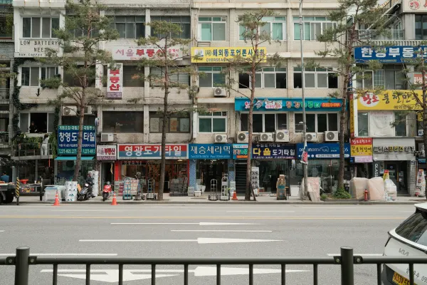 A layered building facade covered with Korean shop signs across a quiet road