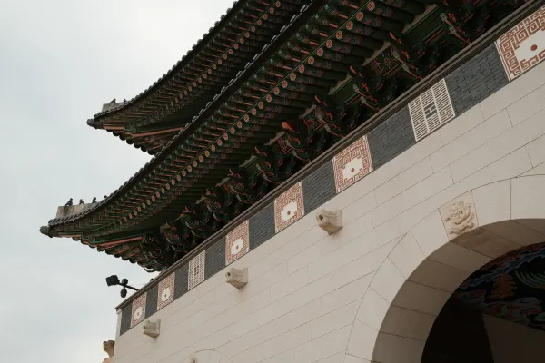 Painted palace eaves sweeping above a white stone gateway