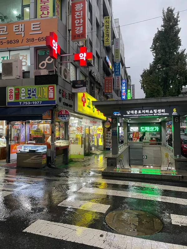 Neon shop signs reflected on a rainy Seoul street