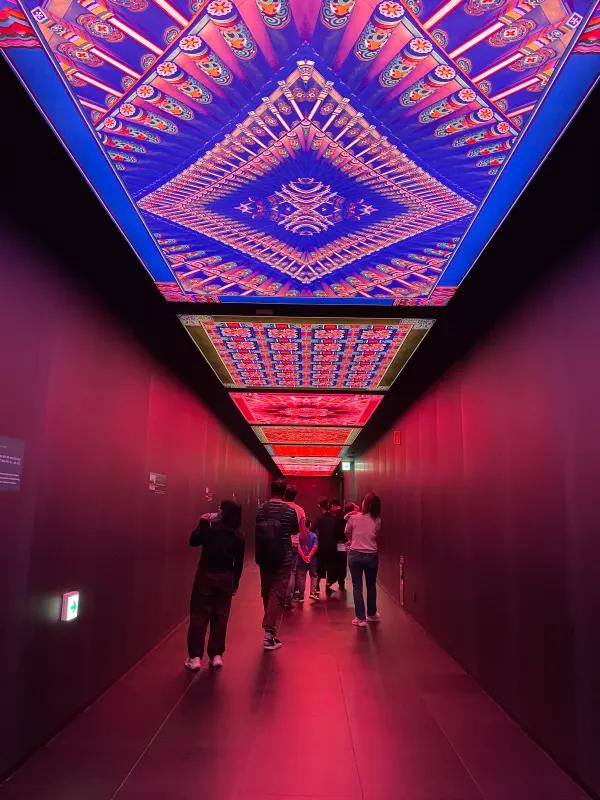 People walking beneath a vivid patterned ceiling installation in Seoul