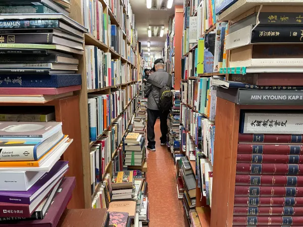 Tall shelves lining a narrow secondhand bookshop aisle