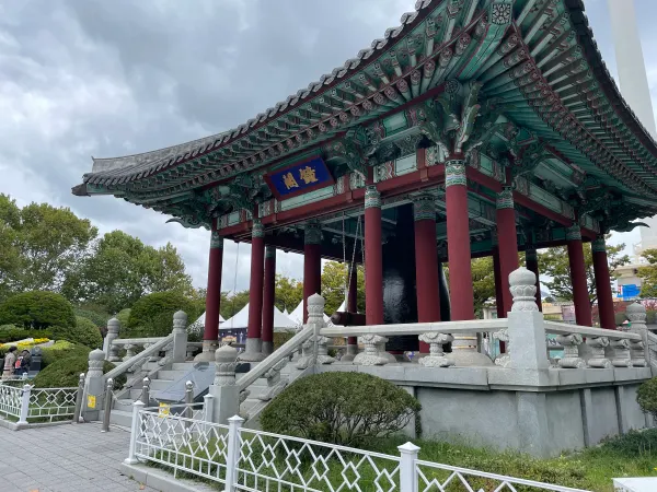 An ornate traditional pavilion framed by trees in Busan