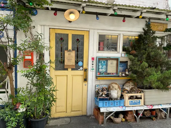 A yellow shop door framed by climbing plants and signs