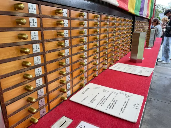 Rows of wooden fortune drawers with brass handles above a red counter