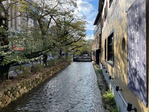 Sunlit canal beside white walls and wooden houses