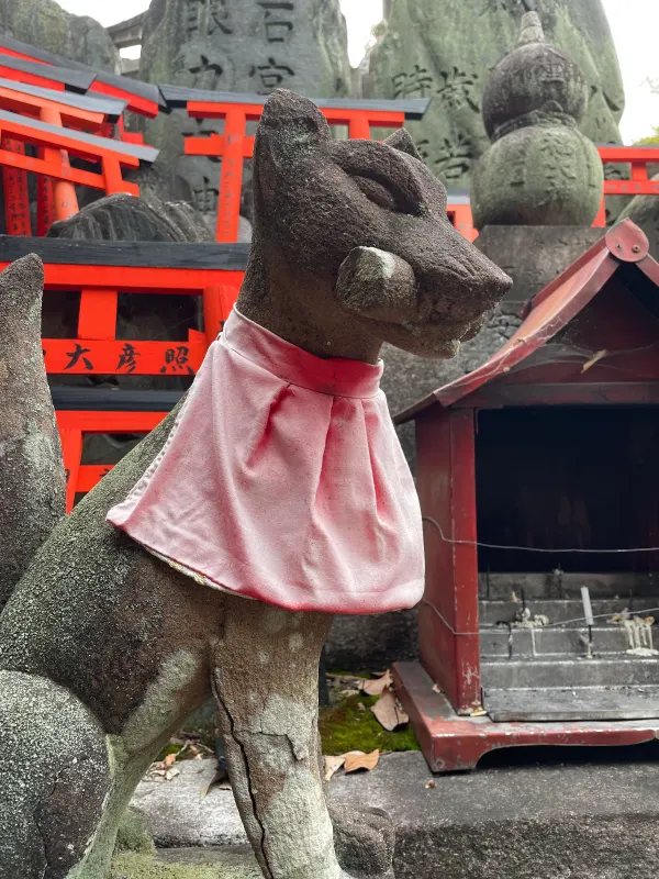 A stone fox statue wearing a pink bib