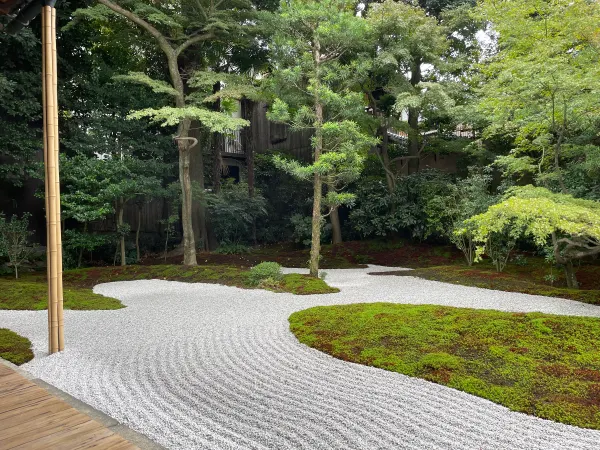 Curving lines in white gravel around a green temple garden