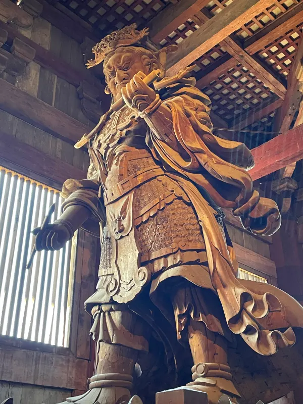 A towering carved guardian inside a wooden temple