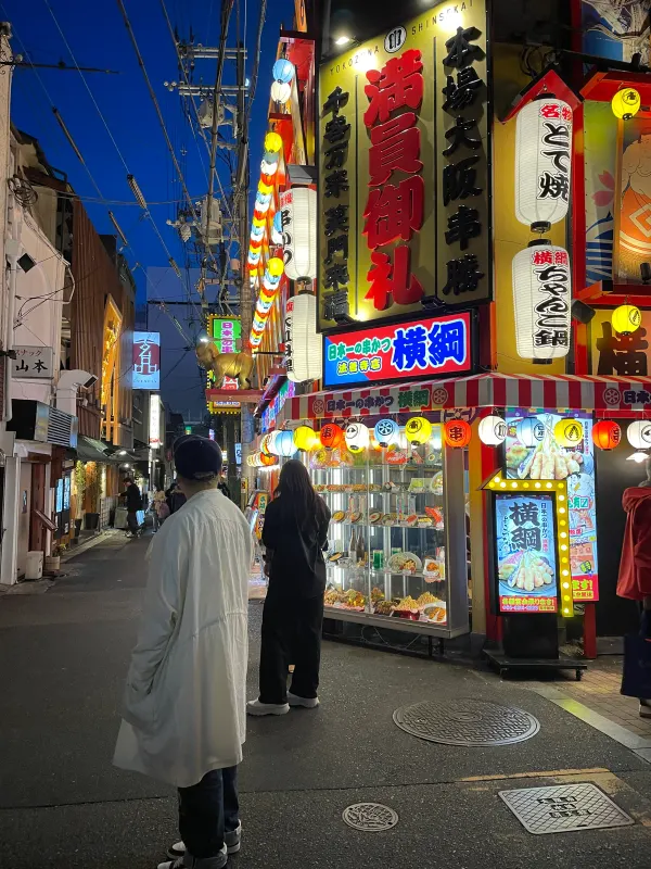 Pedestrians beneath bright street signs at night