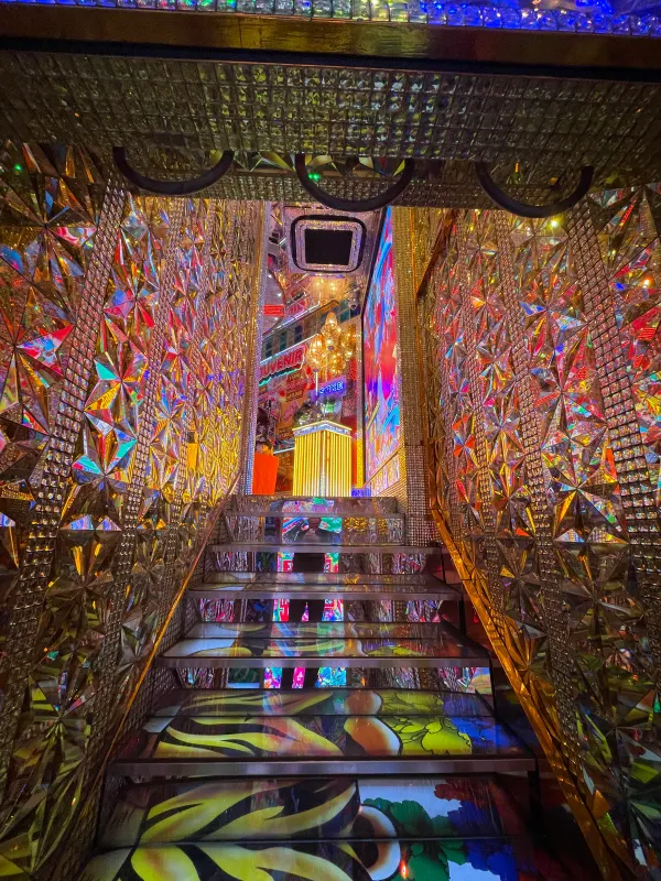 A narrow staircase surrounded by colourful artwork and lights