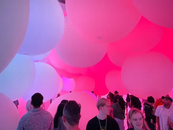 Visitors standing beneath glowing pink and white spheres
