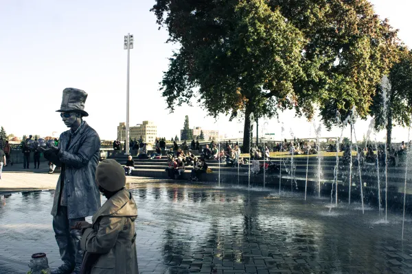 A street performer beside a waterfront fountain