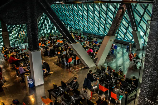 People reading beneath teal glass and diagonal supports in Seattle Central Library