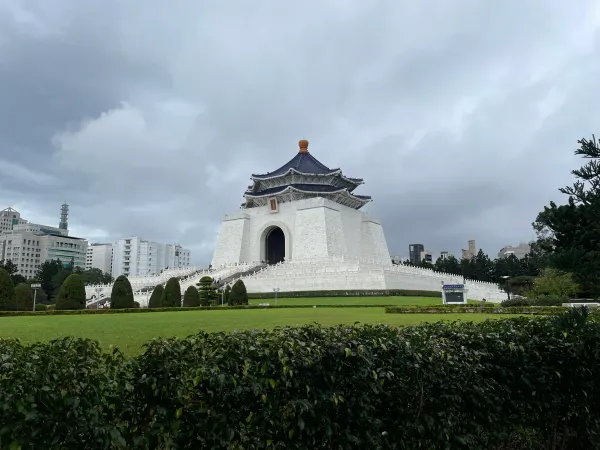 The white memorial hall beyond a green lawn beneath cloudy skies