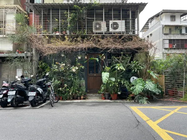Scooters parked outside a café covered in trailing plants