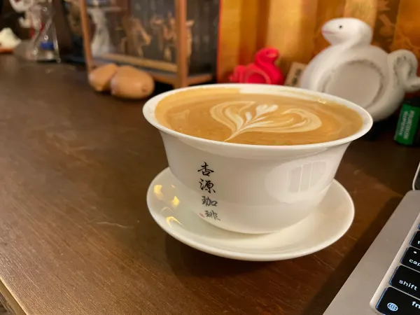 A cup of coffee on a wooden counter surrounded by café ornaments