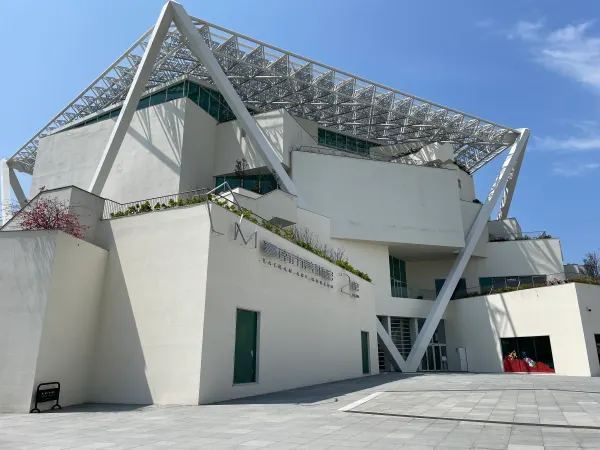 Angular white museum walls beneath a geometric steel canopy