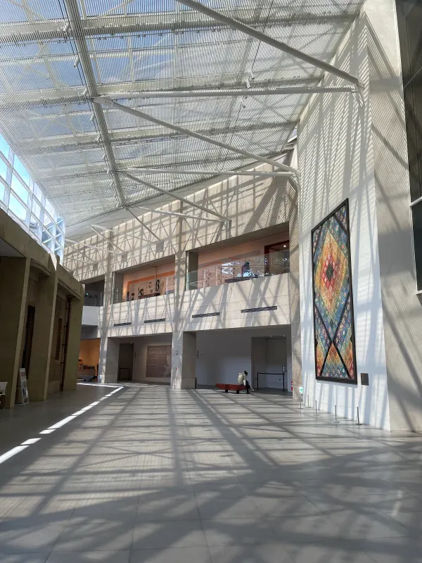 Geometric shadows crossing a bright corridor beneath a glass roof