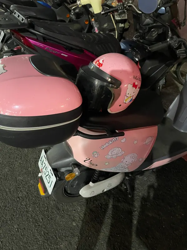 A pink scooter and matching helmet parked on the street