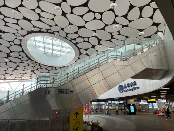 Escalators beneath an oval skylight and circular ceiling panels at Kaohsiung Station