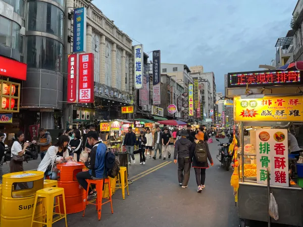 People walking between food stalls at a busy market