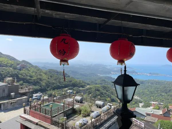 Red lanterns framing the rooftops and coastline below Jiufen